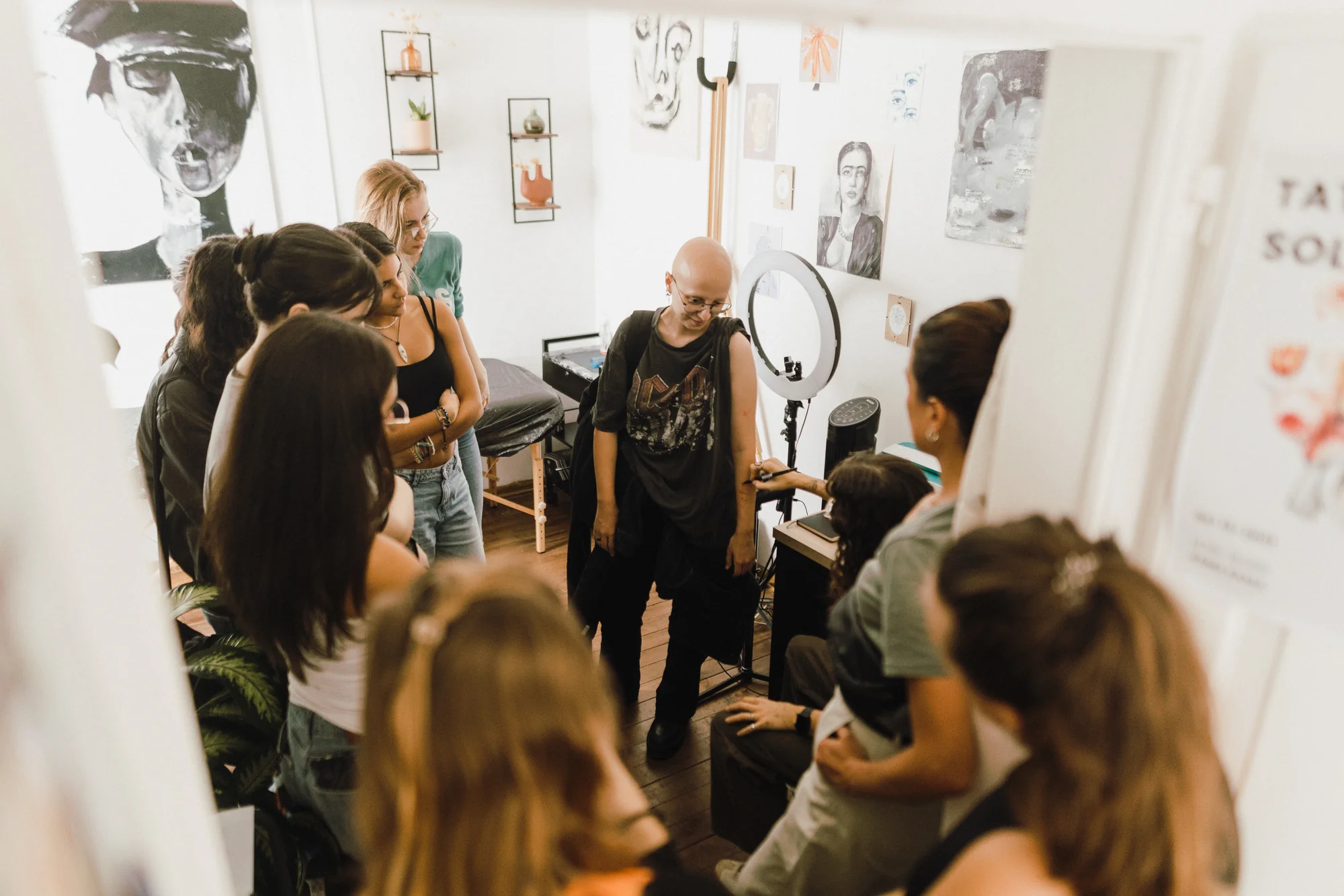 Artista tatuador demonstra a sua técnica a um grupo atento de estudantes