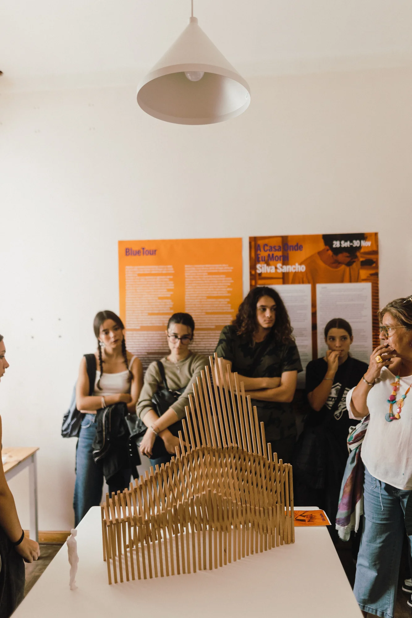 Artista explica uma escultura a um pequeno grupo, luz de contraluz