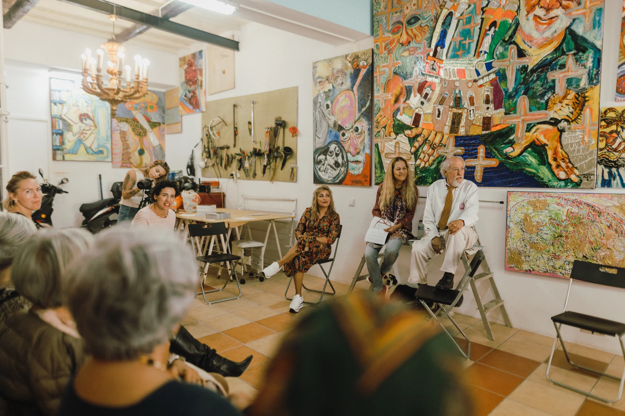 Artista, moderador e audiência sentados entre as pinturas de Vicente de Brito